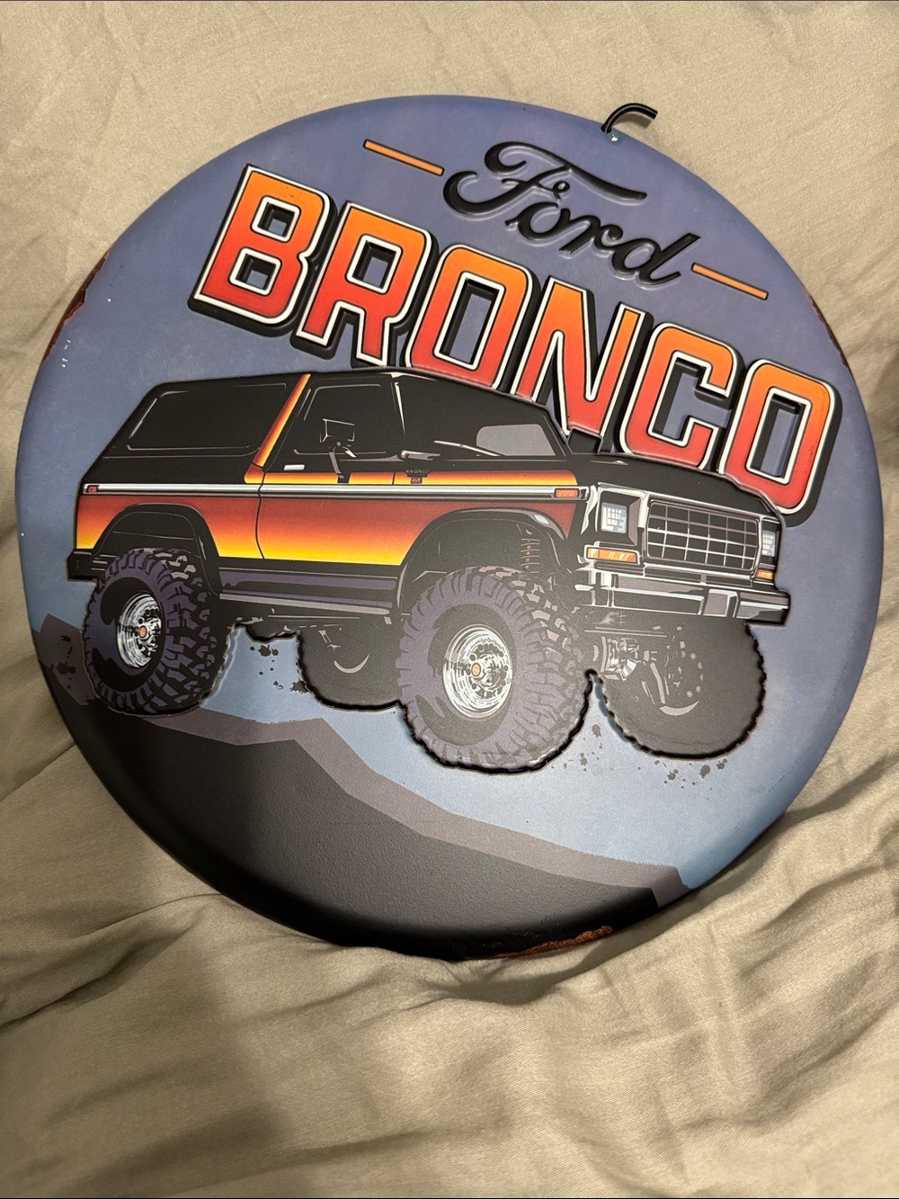 Ford Bronco Round Metal Sign - Blue Background with Orange and Red Accents